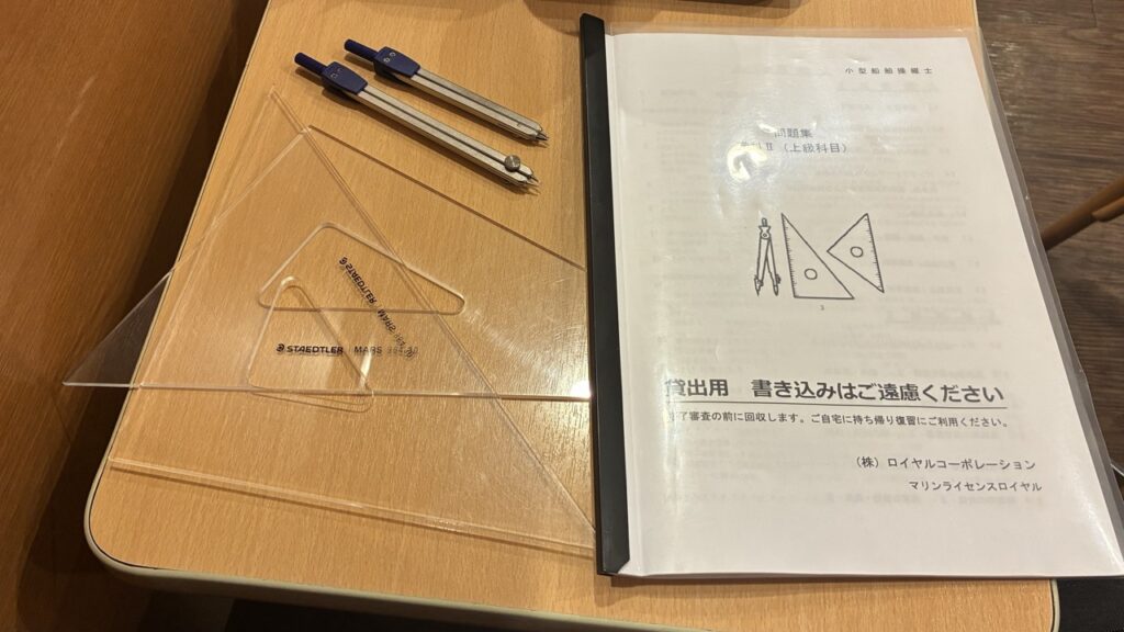 講習で貸し出された問題集と海図作成用の三角定規、コンパス